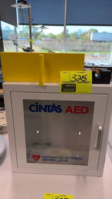 Cintas metal AED cabinet with MERT kit. Features a hinged door with clear viewing window, pull handle, and pre-drilled wall mounting holes. Includes t