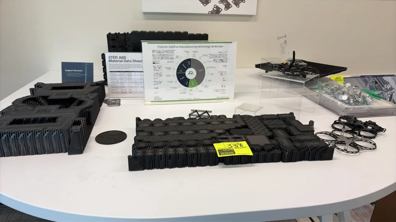 Assorted polymer molded and 3D-printed parts. Includes various black polymer components, nested parts, lattice support structures, and drone frame com