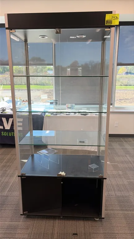 Glass display case. Features an aluminum frame, black top canopy with recessed lighting, 3 adjustable glass shelves, glass display doors with lock, an