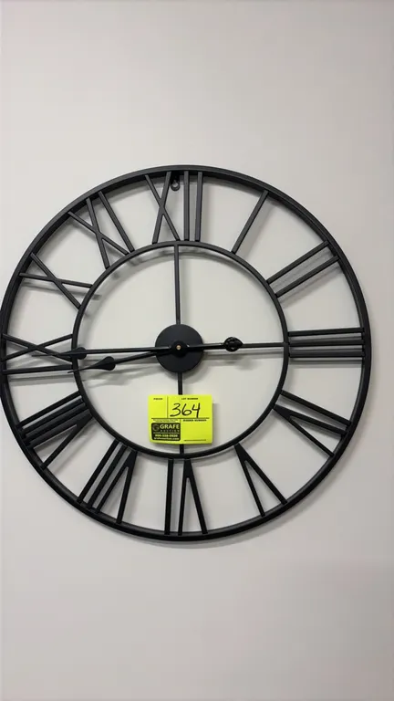 Decorative Roman numeral wall clock. Features an open-face circular metal frame design in a matte black finish with cutout Roman numeral hour markers