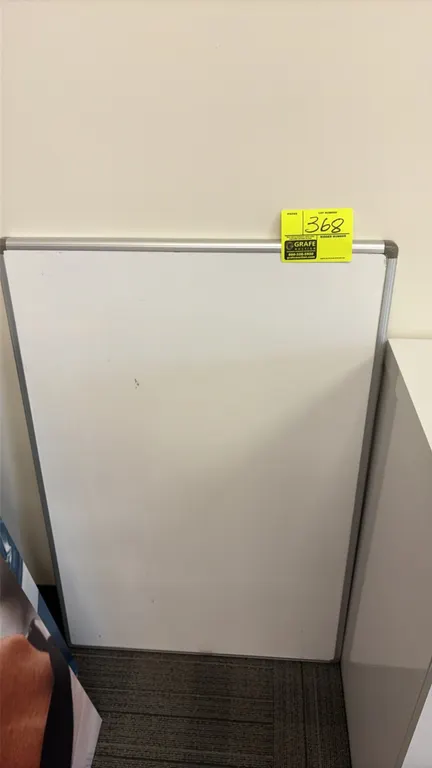 Dry erase board. Features an aluminum frame with protective corner caps and a white writing surface.