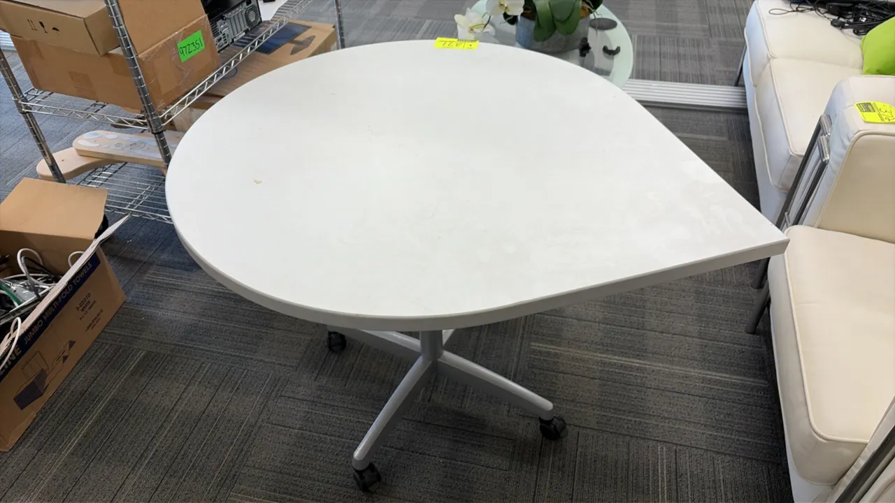 Mobile teardrop table. Features a white laminate top. 36" x 43". Mounted on a silver-tone pedestal with a 4-star caster base.