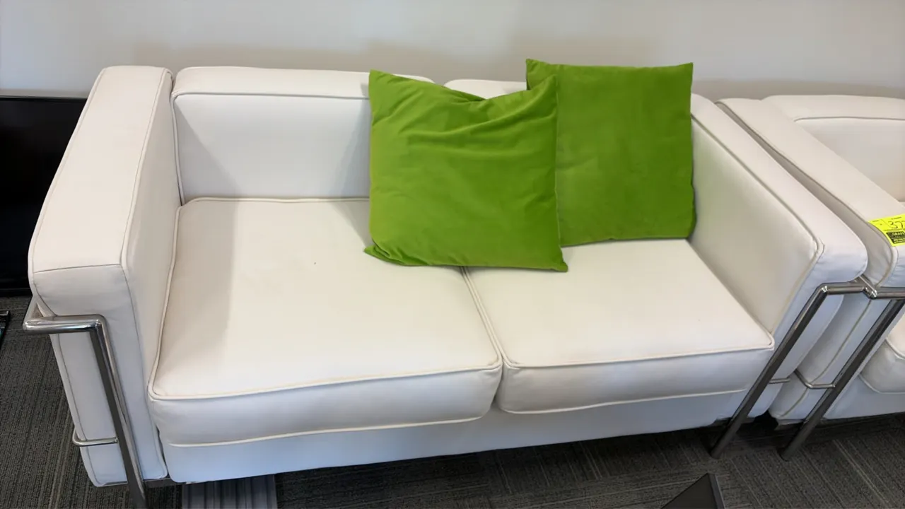 Cream vinyl loveseat with matching armchair. Features chrome-finish tubular metal frames and box cushions. Includes (2) green accent pillows. Loveseat