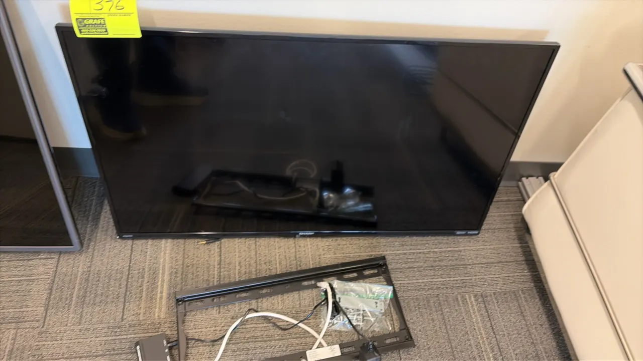 Sharp LC-39LE551U flat screen television. Includes wall mount bracket and mounting hardware. S/N: 40500214820. Electrical: 120V, 60 Hz, 75W.