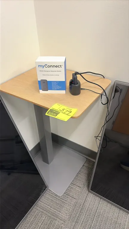 Wood laminate top side table with gray metal pedestal base. 18" x 14". Includes myConnect Mobile Emergency Response System with handheld unit, chargin
