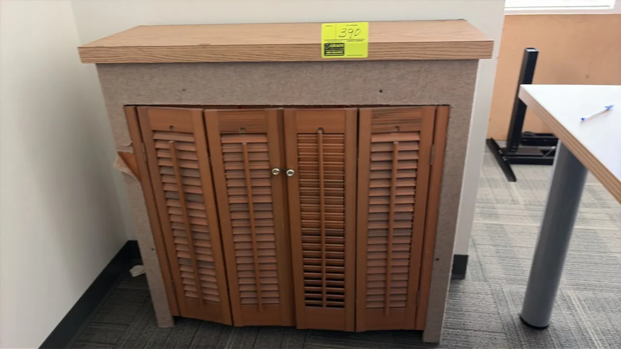 Wood laminate cabinet with louvered doors. Features a wood laminate top, fabric-wrapped exterior frame, interior shelving, and assorted wood pieces in