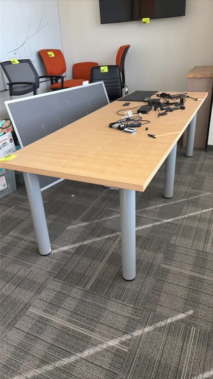 Wood laminate conference table. Features a light woodgrain laminate top and cylindrical metal post legs. 94" x 35 1/2". Includes assorted power cords