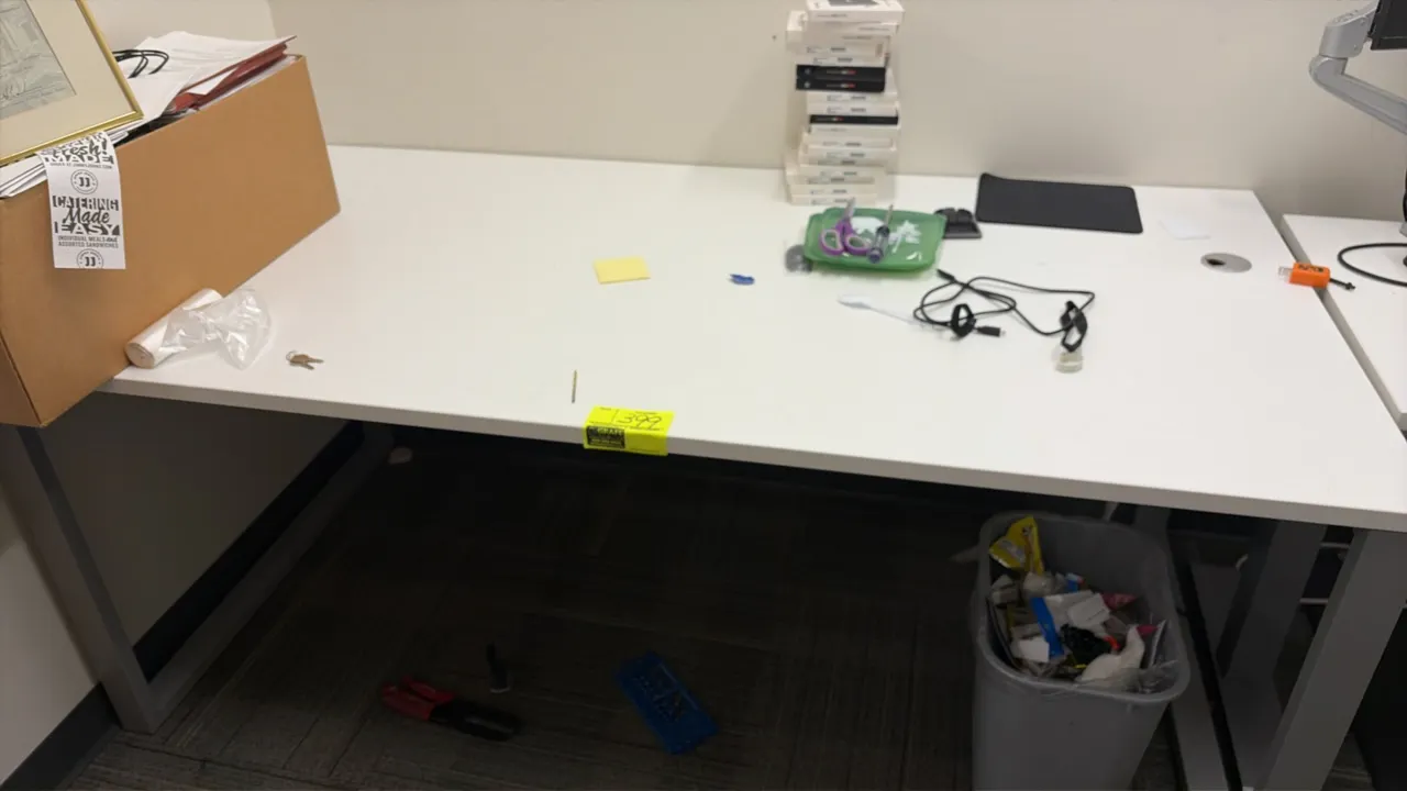 Wood laminate table. Features a white laminate work surface, integrated cable management grommet, and gray metal loop-leg base. 72" x 36". Contents no