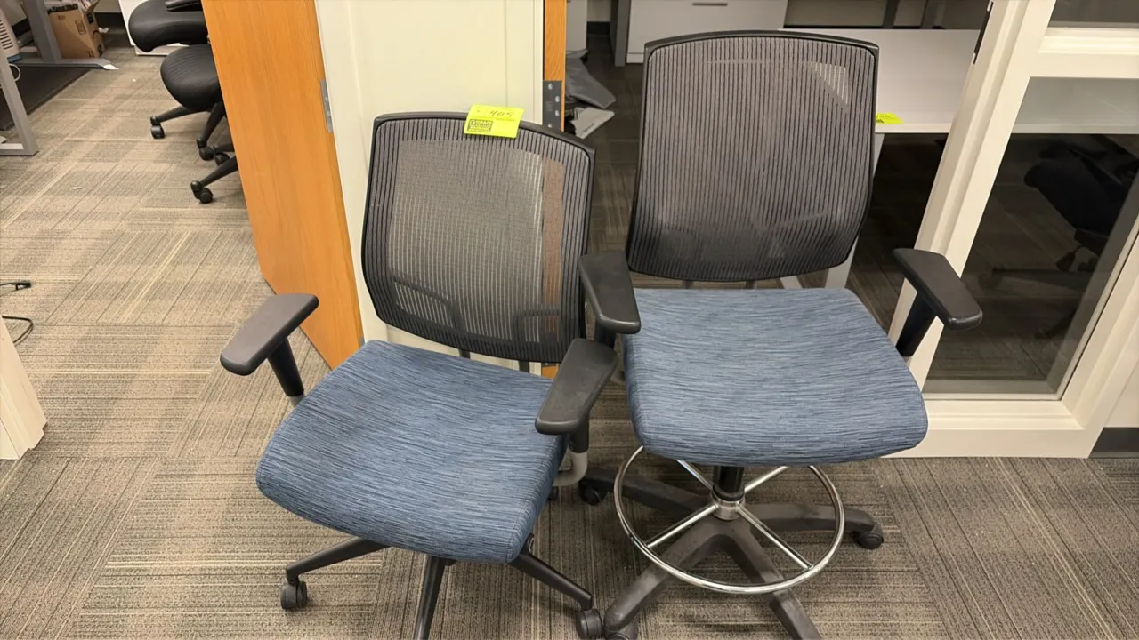 Mesh-back office chairs. Features blue fabric upholstered seats, black mesh backs, and armrests. Includes (1) standard task chair and (1) drafting sto