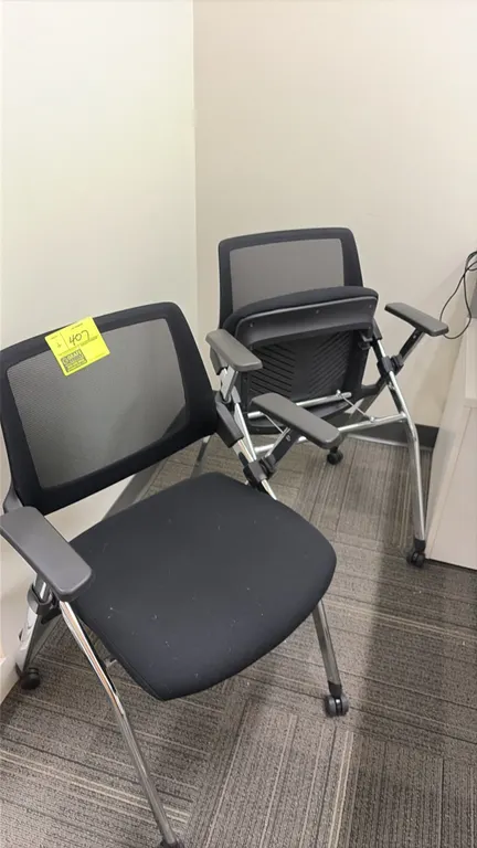 Flip-up nesting office chairs. Features black mesh back, upholstered flip-up seats, fixed armrests, and chrome metal legs. Mounted on casters.