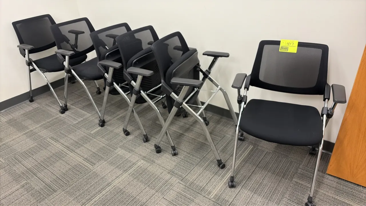 Flip-up nesting conference room chairs. Features black mesh backrests, black upholstered flip-up seats, armrests, and chrome-finished metal frames. Mo