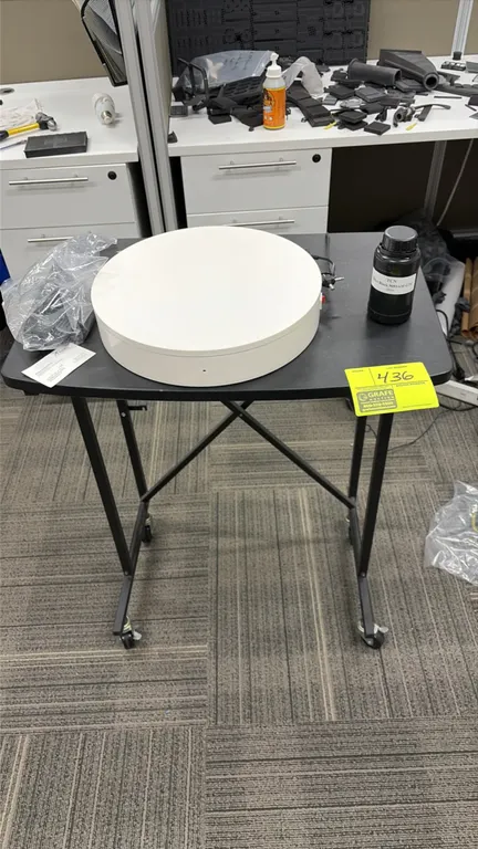 Portable rolling workstation with contents. Features black laminate top and black metal frame mounted on casters. Includes electric rotating display t