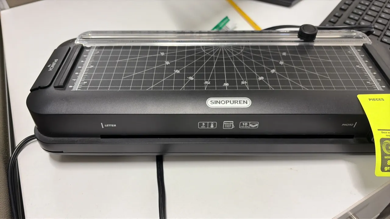Sinopuren thermal laminator. Features built-in sliding paper trimmer with alignment grid and angle guides, integrated hole punch, and attached power c