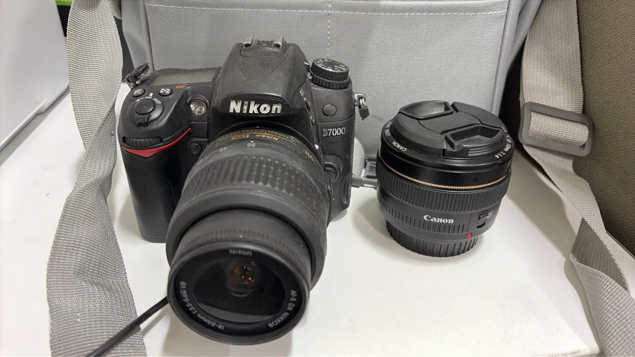 Nikon D7000 DSLR camera package. Includes Nikon AF-S DX Nikkor 18-55mm f/3.5-5.6G VR lens, Canon EF 50mm f/1.4 lens, charger with cable, neck strap, a