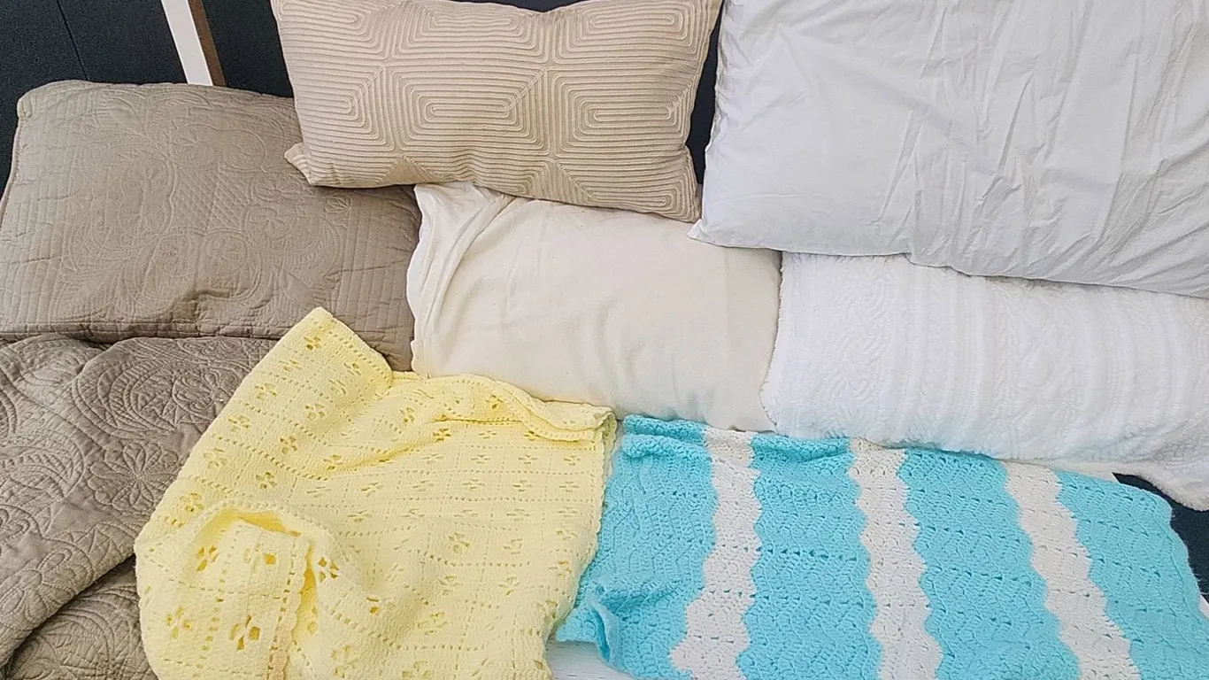 6 Pillows, Yellow and Blue Throw Blankets, and Beige Quilted Coverlet