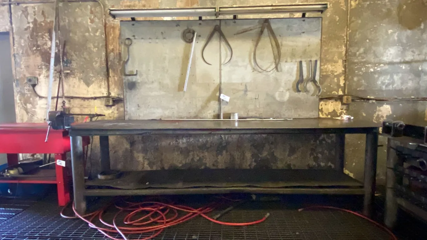 STEEL WORK BENCH WITH LIGHTED BACKBOARD AND ATTACHED VISE - APPROX. 10 1/2FT X 3FT X 7FT HIGH TO