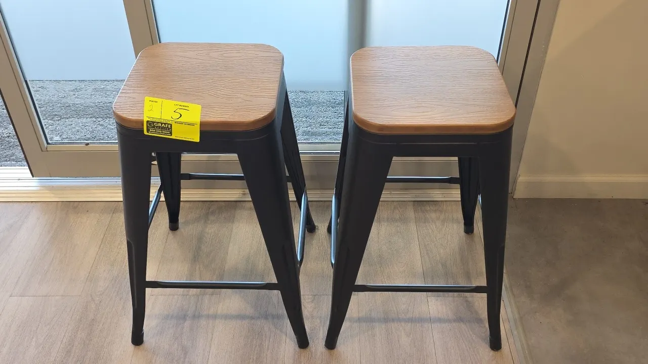 2023 LumiSource stools. Features woodgrain laminate tops and black metal frames with integrated footrests. 24"H.