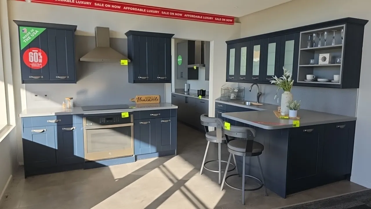 Wren Kitchens Infinity Plus upper and lower kitchen cabinets. Features dark blue finish, solid surface countertops with backsplash, single-basin stain