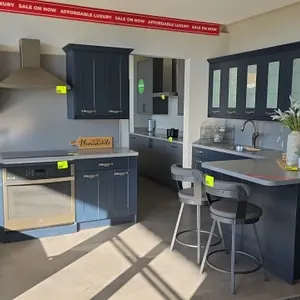 Wren Kitchens Infinity Plus upper and lower kitchen cabinets. Features dark blue finish, solid surface countertops with backsplash, single-basin stain