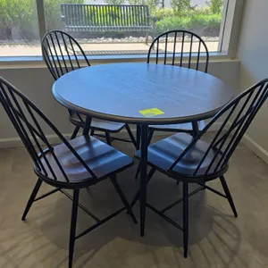 Dining table and chair set. Includes (1) round laminate dining table and (4) spindle-back dining chairs. Features dark woodgrain laminate top with bla