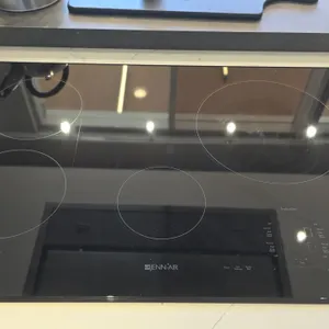 JennAir JIC4430XB 4-burner induction cooktop. Features black ceramic glass surface, digital touch controls, bridge function, sensor boil, and control 
