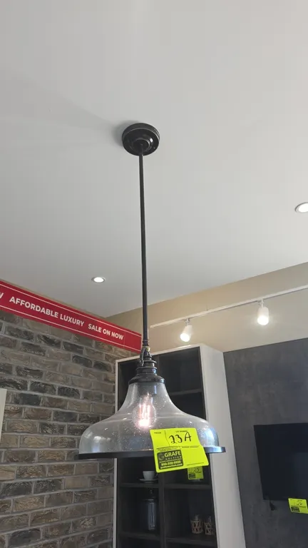 Metal and glass pendant light fixture. Features clear seeded glass shade, dark metal downrod and trim, ceiling mounting canopy, and single bulb socket