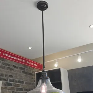 Metal and glass pendant light fixture. Features clear seeded glass shade, dark metal downrod and trim, ceiling mounting canopy, and single bulb socket