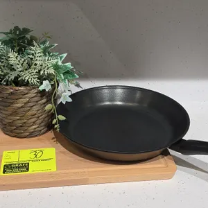 Assorted kitchen smallwares and decor. Includes non-stick frying pan, wooden cutting board, artificial plant in woven basket planter, white embossed c