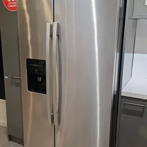 2022 Amana ASI2575GRS08 side-by-side refrigerator and freezer. Features a stainless steel finish, exterior door ice and water dispenser, interior glas
