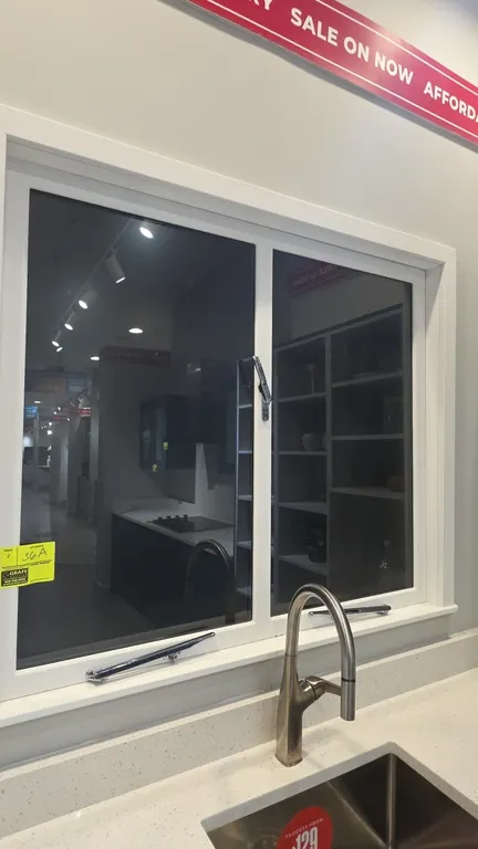 Casement windows. Features white frame, clear glass panes, and chrome locking latches and bottom stay bars. Countertop, faucet, and background items n