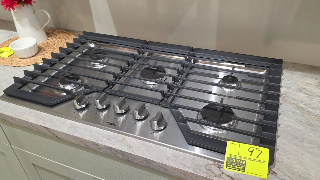 Whirlpool WCG55US6HS00 36" 5-burner natural gas cooktop. Features stainless steel surface, continuous cast iron grates, and front control knobs. S/N: