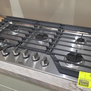 Whirlpool WCG55US6HS00 36" 5-burner natural gas cooktop. Features stainless steel surface, continuous cast iron grates, and front control knobs. S/N: 