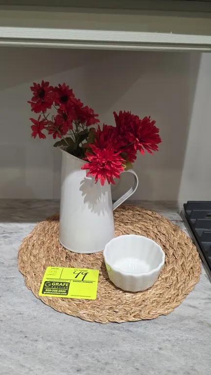 Assorted decorative kitchen smallwares. Includes white pitcher with faux florals, fluted ceramic ramekin, round woven placemat, (2) glass canisters wi