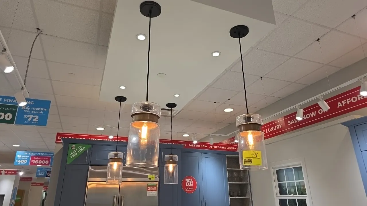 Glass pendant lights. Features clear cylindrical glass shades with brass-tone metal collar accents, black hanging cords, and round black ceiling canop