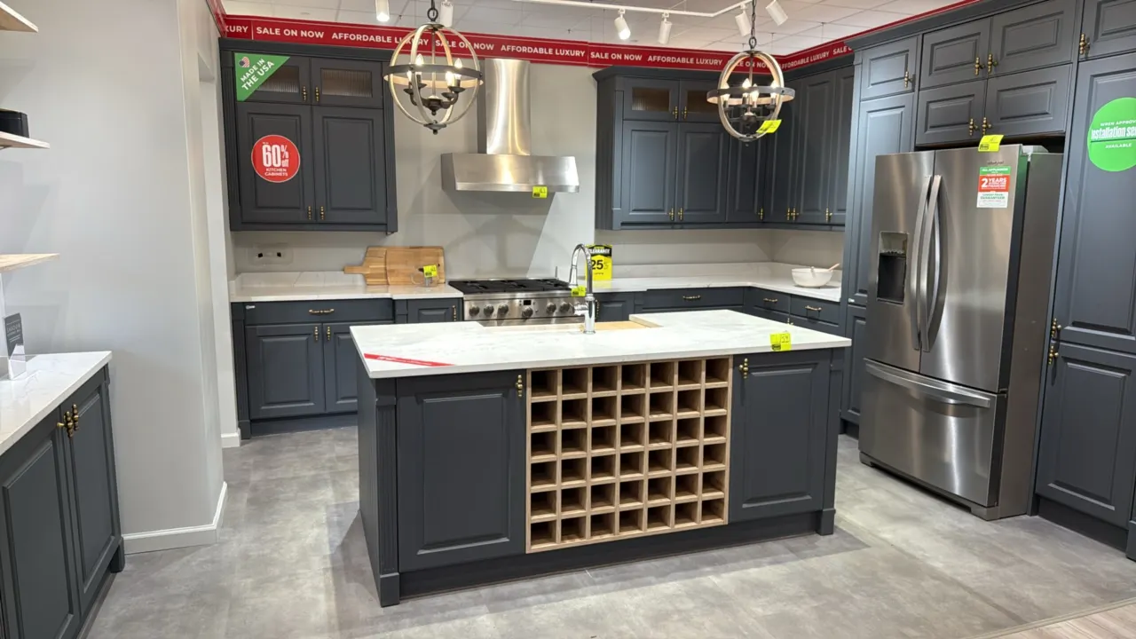 Infinity Plus kitchen cabinets. Features quartz countertops, island with built-in wine rack, apron-front sink with faucet, pull-out tall pantry, and s