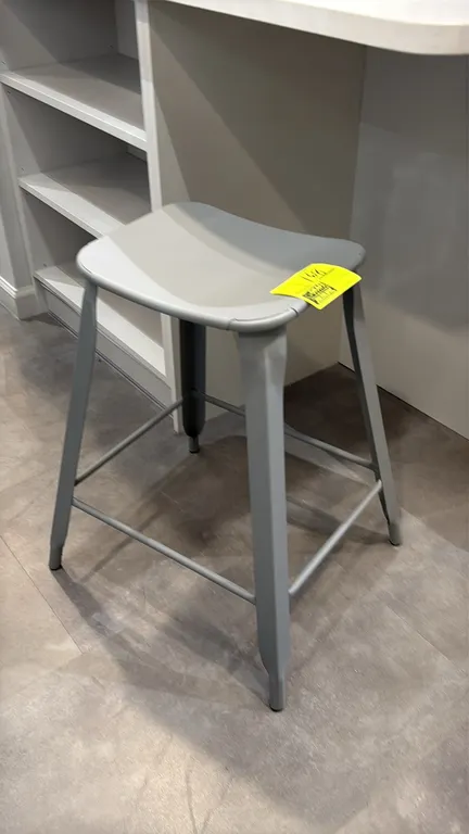 Metal counter stool. Features a backless design, gray finish, and perimeter footrest stretchers. 24"H.