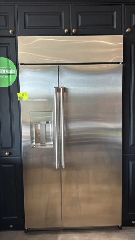 Café side-by-side refrigerator-freezer. Features stainless steel finish, exterior AutoFill water and ice dispenser, tubular handles, adjustable glass