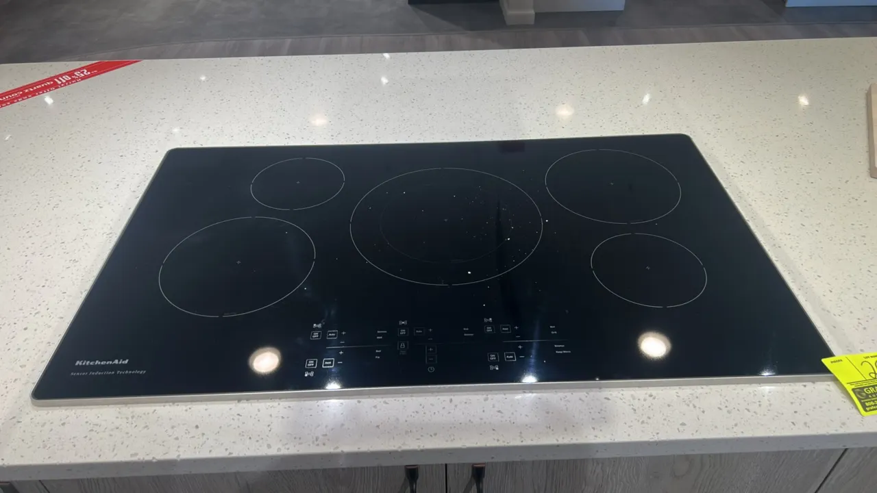 KitchenAid 5-element sensor induction cooktop. Features black ceramic glass surface with stainless steel edge trim, digital touch controls, and center