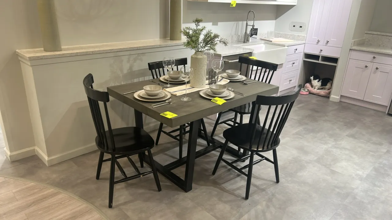 Wooden dining table with (4) wooden chairs. Features a gray-tone wood top with black trestle base, accompanied by (4) black spindle-back dining chairs