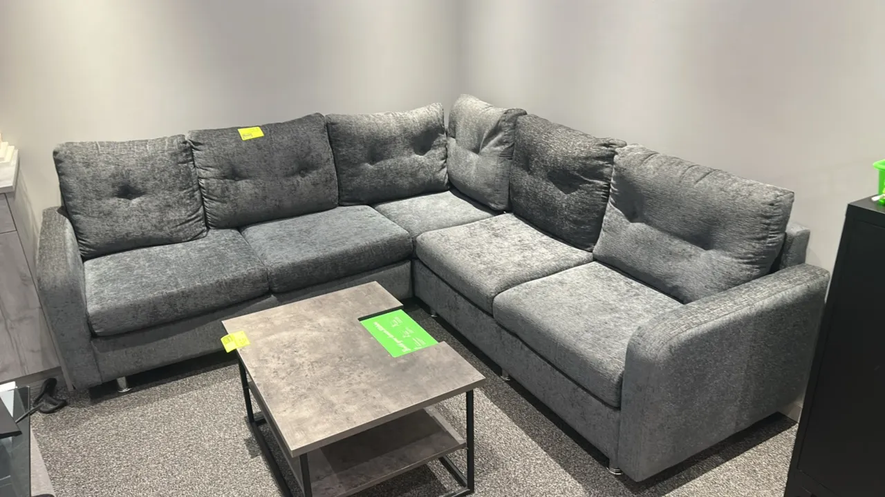 L-shaped cushioned sectional lounge sofa. Features gray textured fabric upholstery, tufted back cushions, and chrome-finish feet. 92" x 92". Coffee ta