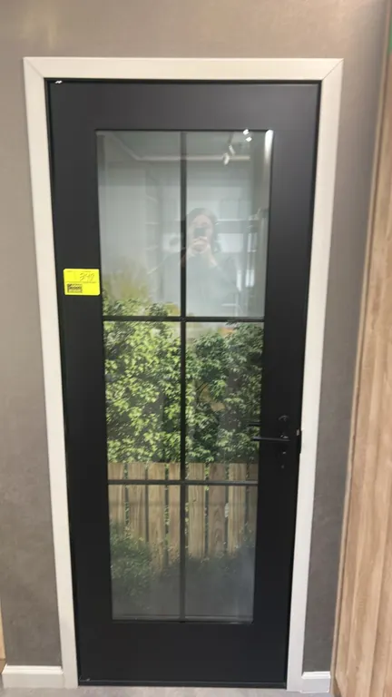 Metal glass panel door. Features a black finish, 6-lite divided glass panel insert, and black lever handle hardware. 29"W x 80"H.