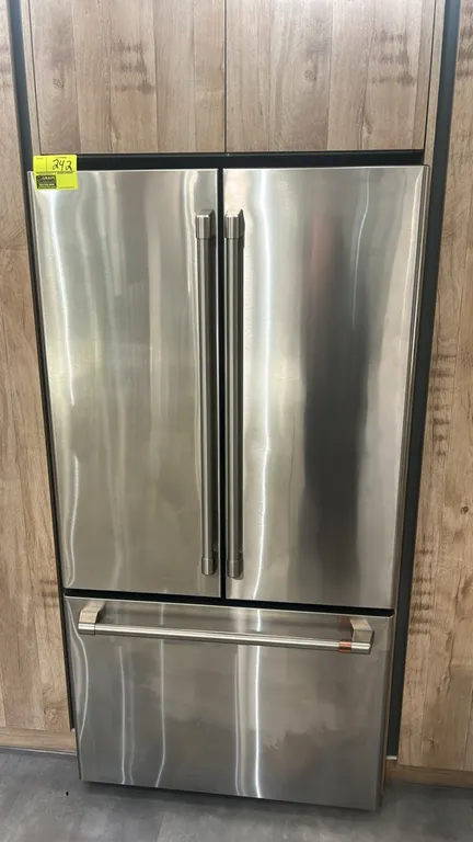 Café CWE23SP2MJS1 French door refrigerator and freezer. Features stainless steel finish with signature copper handle accents, French door upper refrig