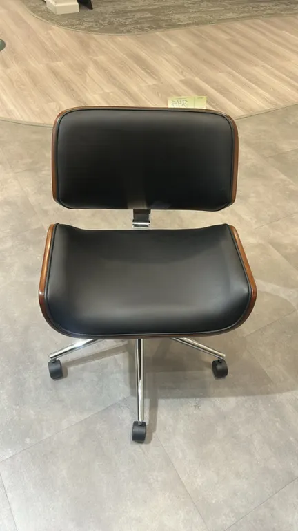 Mid-century modern style armless office chair. Features a molded bentwood shell with walnut finish and black upholstered cushioned seat and back. Equi