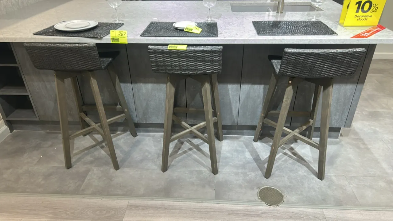 Wicker barstools. Features dark woven wicker low-back seats and solid wood frames with tapered legs and integrated cross-stretcher footrests. Countert