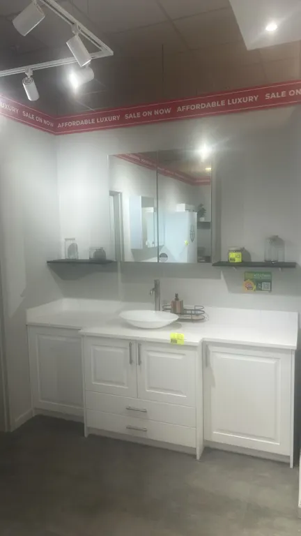 Infinity Plus laminate bathroom vanity suite. Features white cabinetry with solid surface countertop, backsplash, vessel sink, single-handle faucet, a