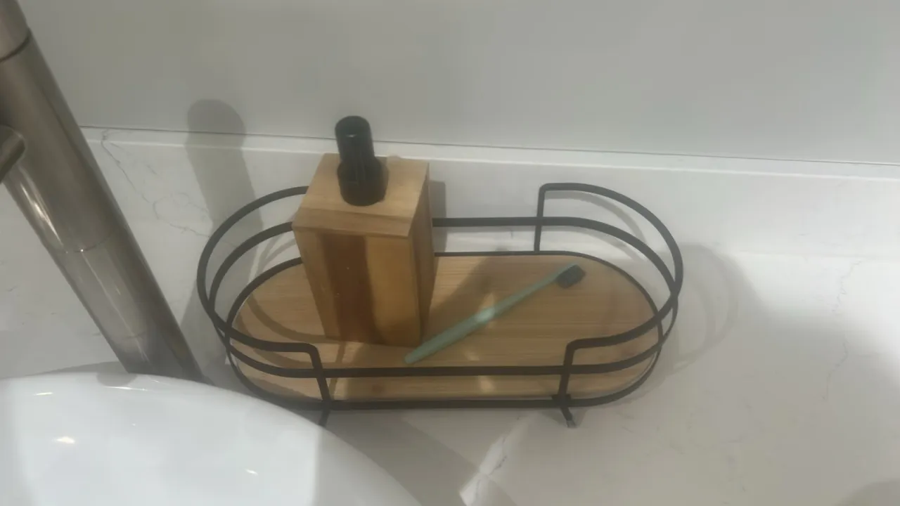 Assorted bathroom accessories and smallwares. Includes wire caddy with wood base, wood soap dispenser, toothbrush, and (2) glass jars with wood lids.