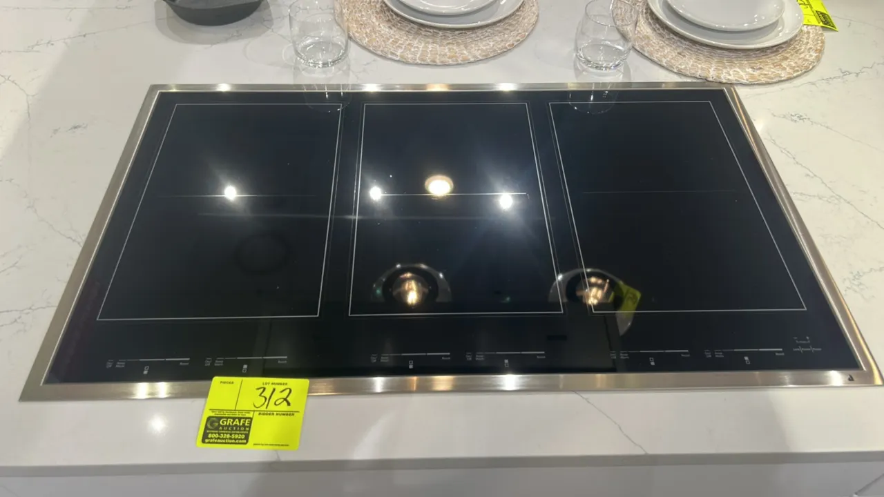 JennAir JIC4736HS electric induction cooktop. Features smooth black ceramic glass surface, stainless steel perimeter trim, and digital touch controls.