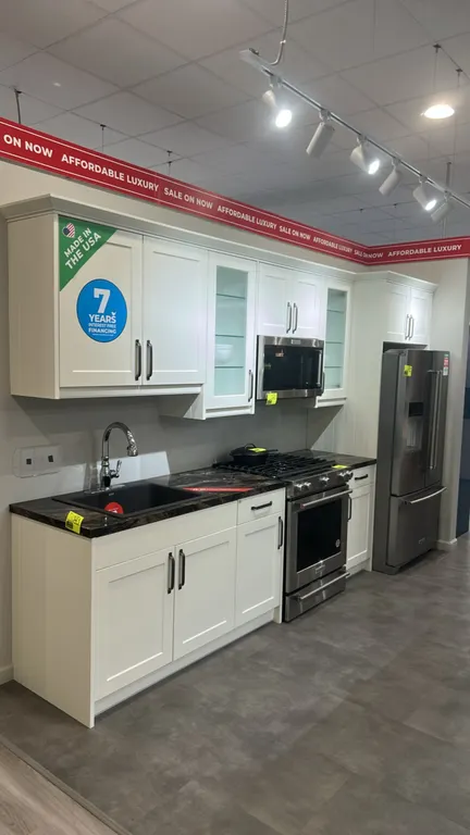Infinity Plus kitchen cabinet suite. Features white shaker-style wall and base cabinets, reeded glass accent upper doors, dark laminate countertops, B