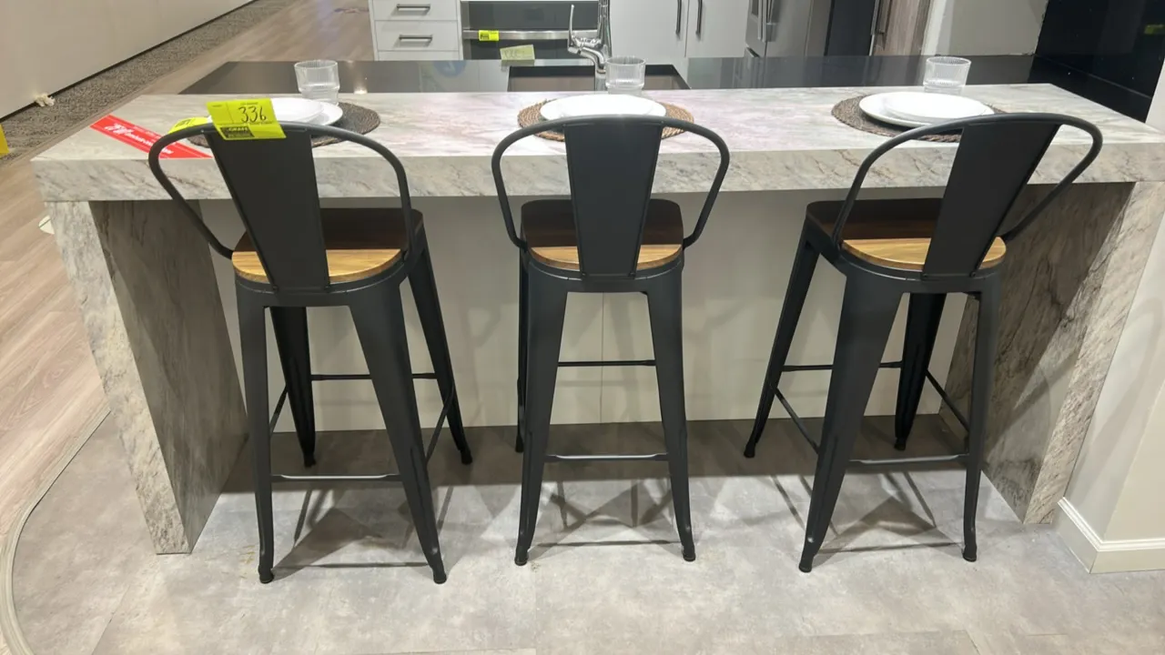 Metal barstools with wooden seats. Features matte black finished metal frames, curved low backrests, wooden seats, and integrated perimeter footrests.