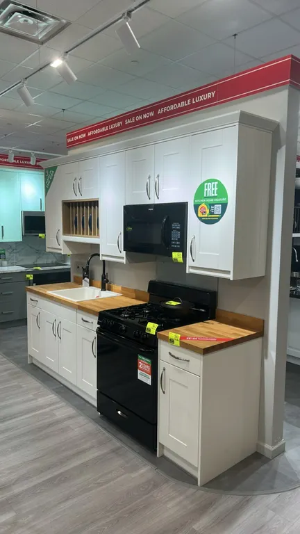 Infinity Plus laminate kitchen cabinet display. Features upper and lower shaker-style cabinets, integrated plate rack, butcher block countertop, Blanc